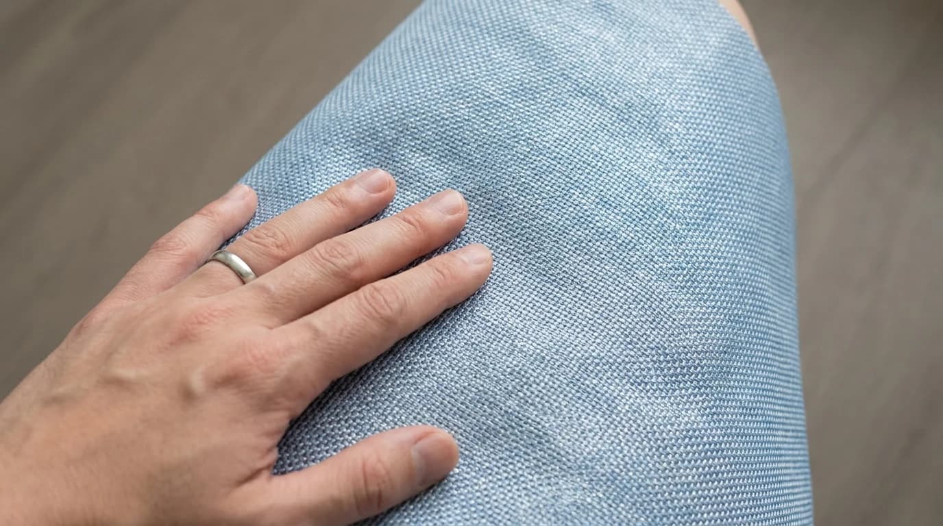 A close overhead view of a hand pressed flat against the fine woven surface of a pale blue cool-touch fabric mat.